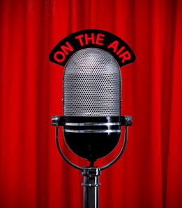 Old-fashioned microphone in front of red curtain, with the phrase 